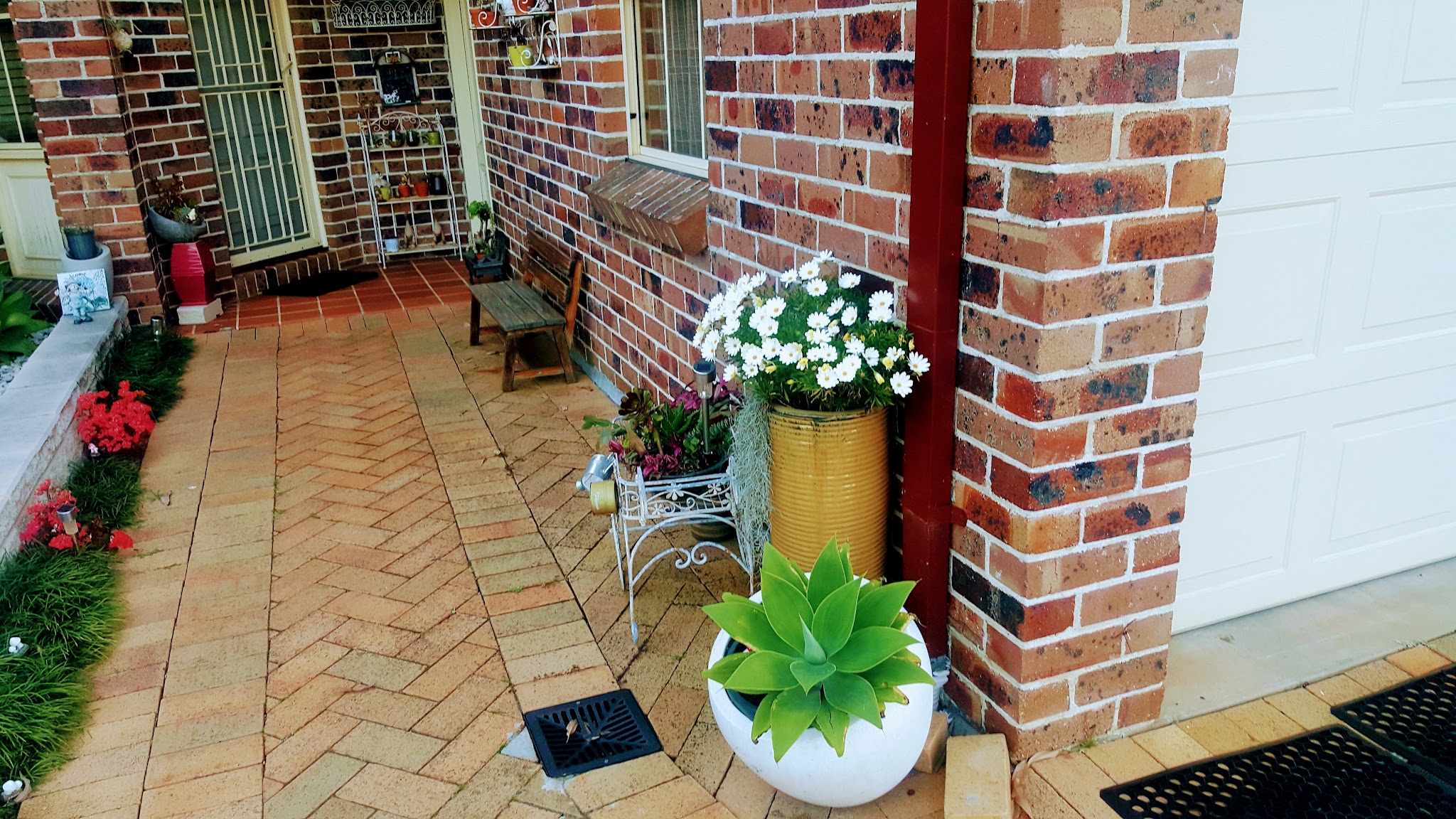 A tidied front entry, herringbone brick path swept and planted pots arranged along the porch.